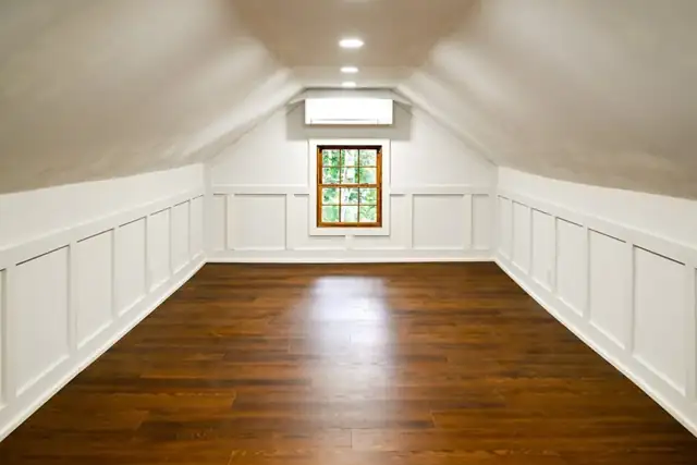Finished attic in Ann Arbor with white wainscot panels, a hardwood floor and a sloped ceiling