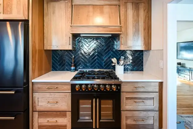 Ann Arbor, MI kitchen with navy herringbone tile backsplash, black range and wood cabinets