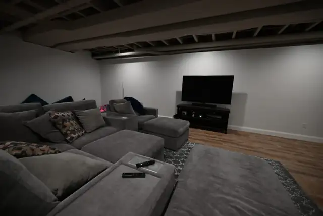 Finished basement home theater with sectional sofa and wall-mounted TV built by Wright's Renovations