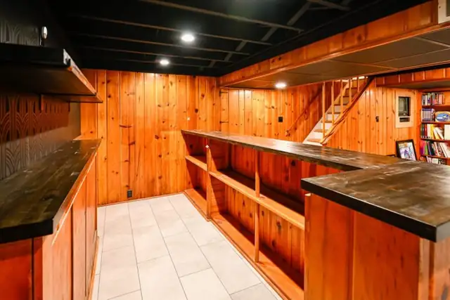 Ypsilanti, MI finished basement with knotty pine walls and a wet bar near the stairs