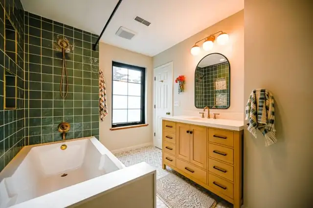 Dexter, MI bathroom remodel with green wall tile, brass fixtures, soaking tub and wood vanity